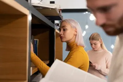 Three friends looking for books in a library during study session