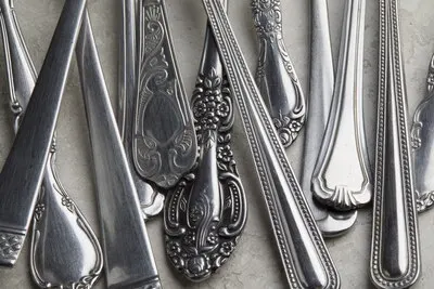 Lot of silver forks and spoons with antique patterns on a white surface