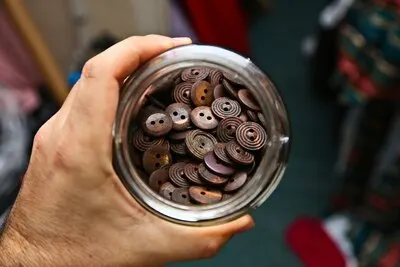 High angle shot of a person holding a jar full of brown buttons