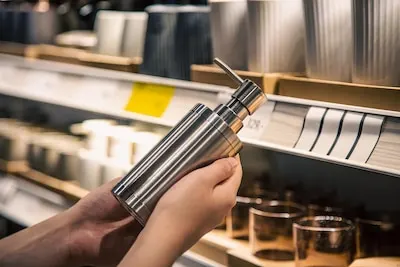 Close up a dispenser for liquid soap in female hands in the store