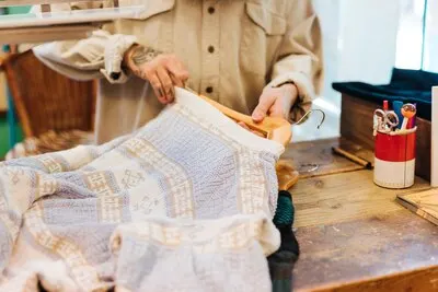 Close-up of a man's hand arranging the clothes on the hanger in the shop