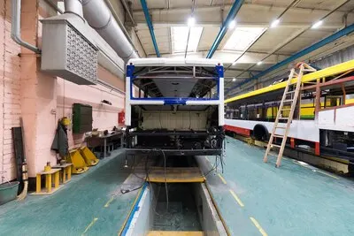 One working day of modern automatic bus manufacturing with unfinished cars workers in protective uniform automotive parts background