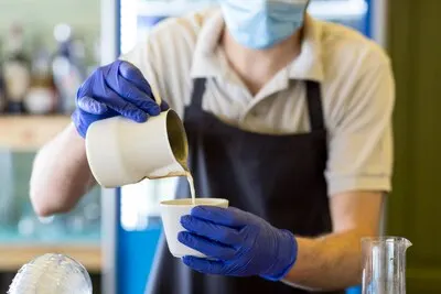 Close-up waiter with gloves preparing coffee