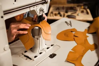 Close up of a male craftsman stitching leather parts