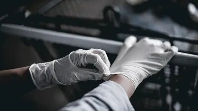 Hand wearing a latex glove while pushing a shopping cart to prevent coronavirus contamination