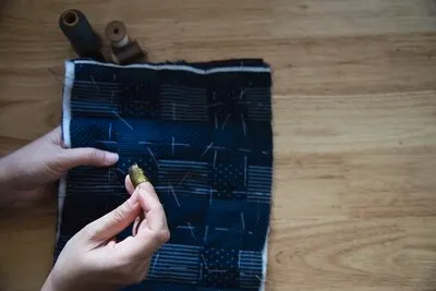 Vintage woman sewing cloth by hand with embroidery set on wooden table - people and handmade diy housework concept