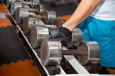 Hand picking up old dumbbell on the rack