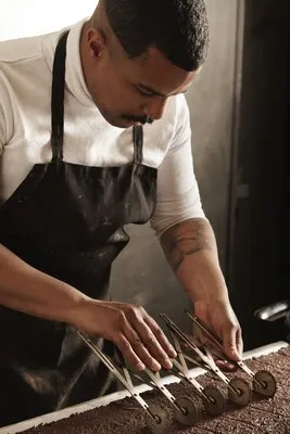 Professional chef black man uses old vintage separator to mark pieces on freshly baked chocolate cake