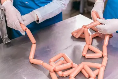 Employees sorting produced meat sausages