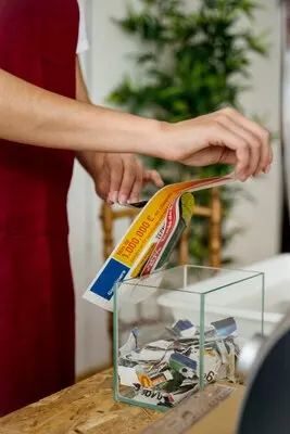 Close-up of a woman's hand tearing paper over transparent glass container